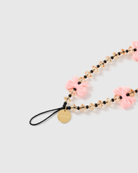 Close-up of the gold-tone engraved STICKYZOO disc on a black stretch-cord loop, next to faceted honey beads and a glossy pink bow