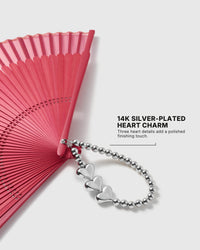 Camellia chiffon folding hand fan held against a soft peach background
