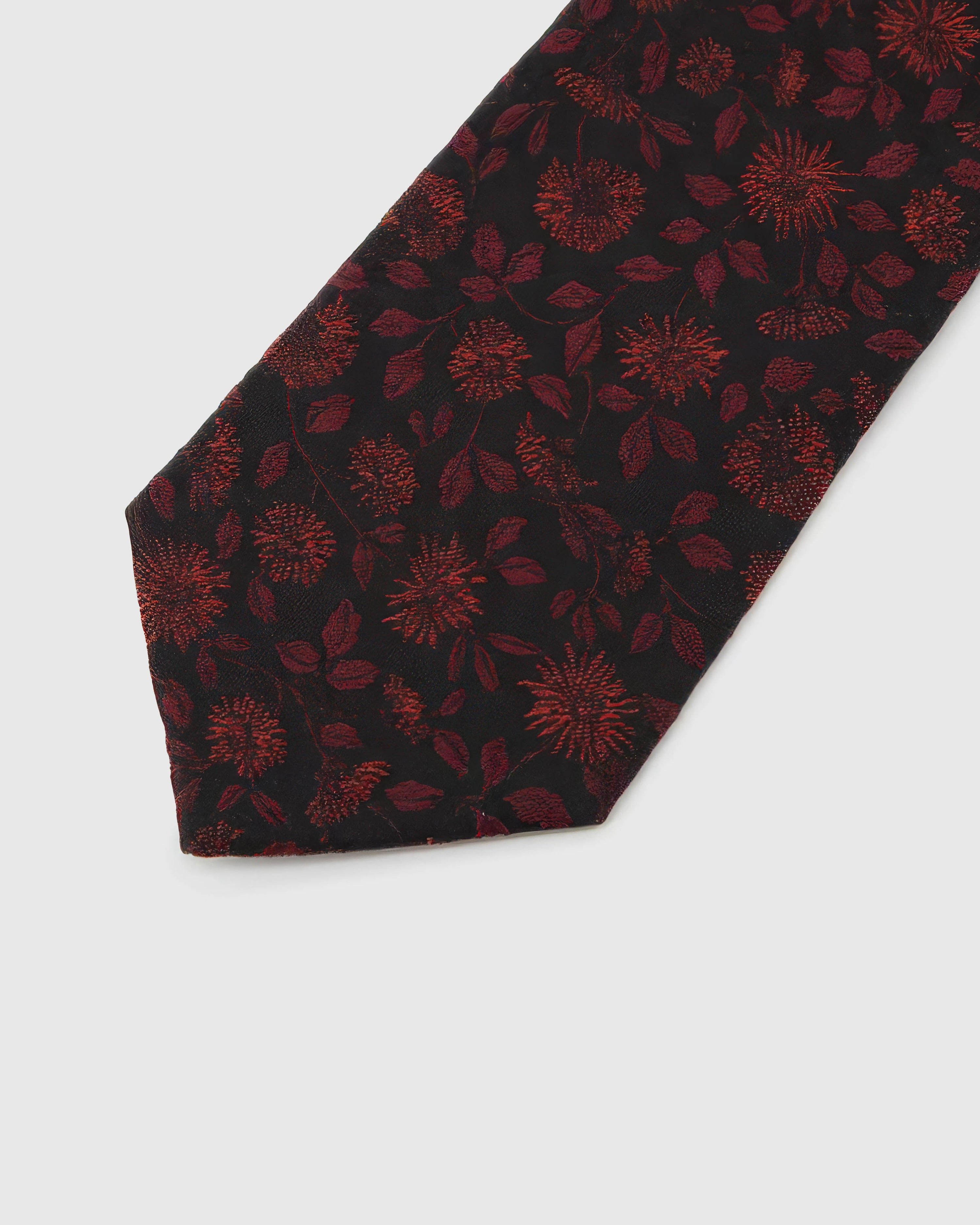 Noir Crimson Bloom Tie detail showing crimson botanical blooms and leaves, raised thread and the tactile noir silk surface.