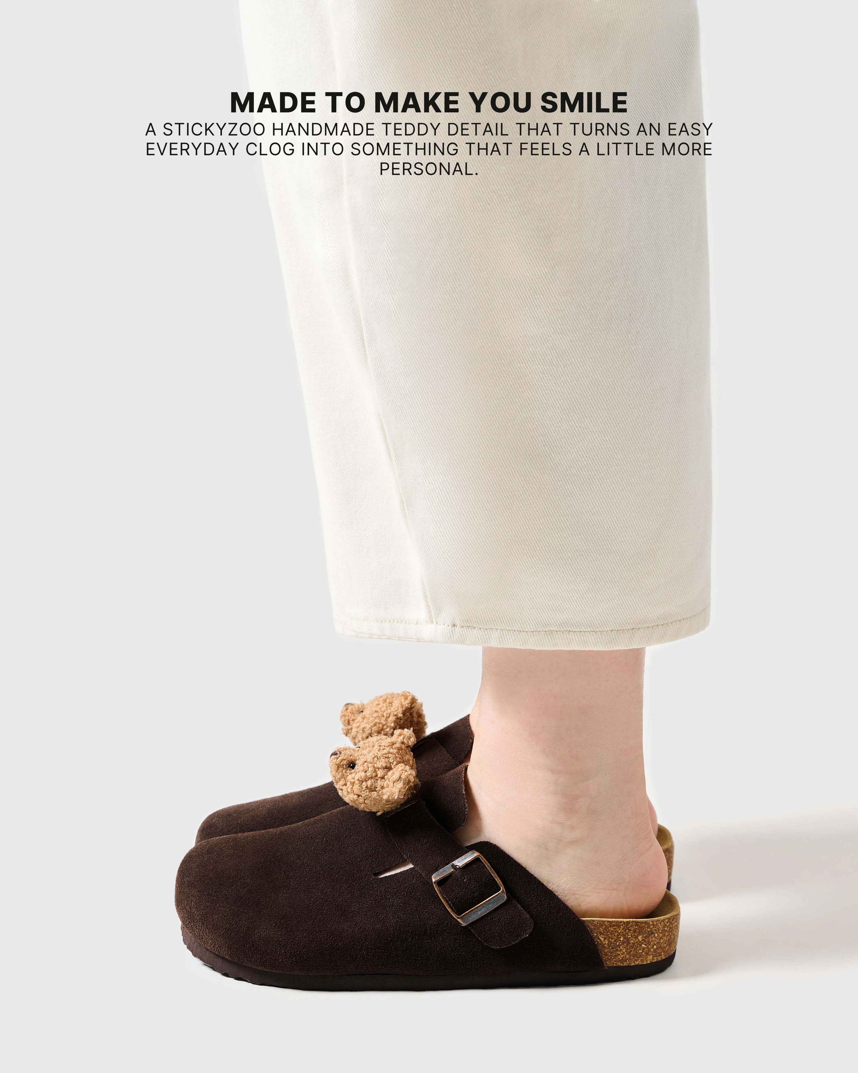 Teddy bear brown suede clogs worn on foot, showing the light tan plush face and slip-on shape