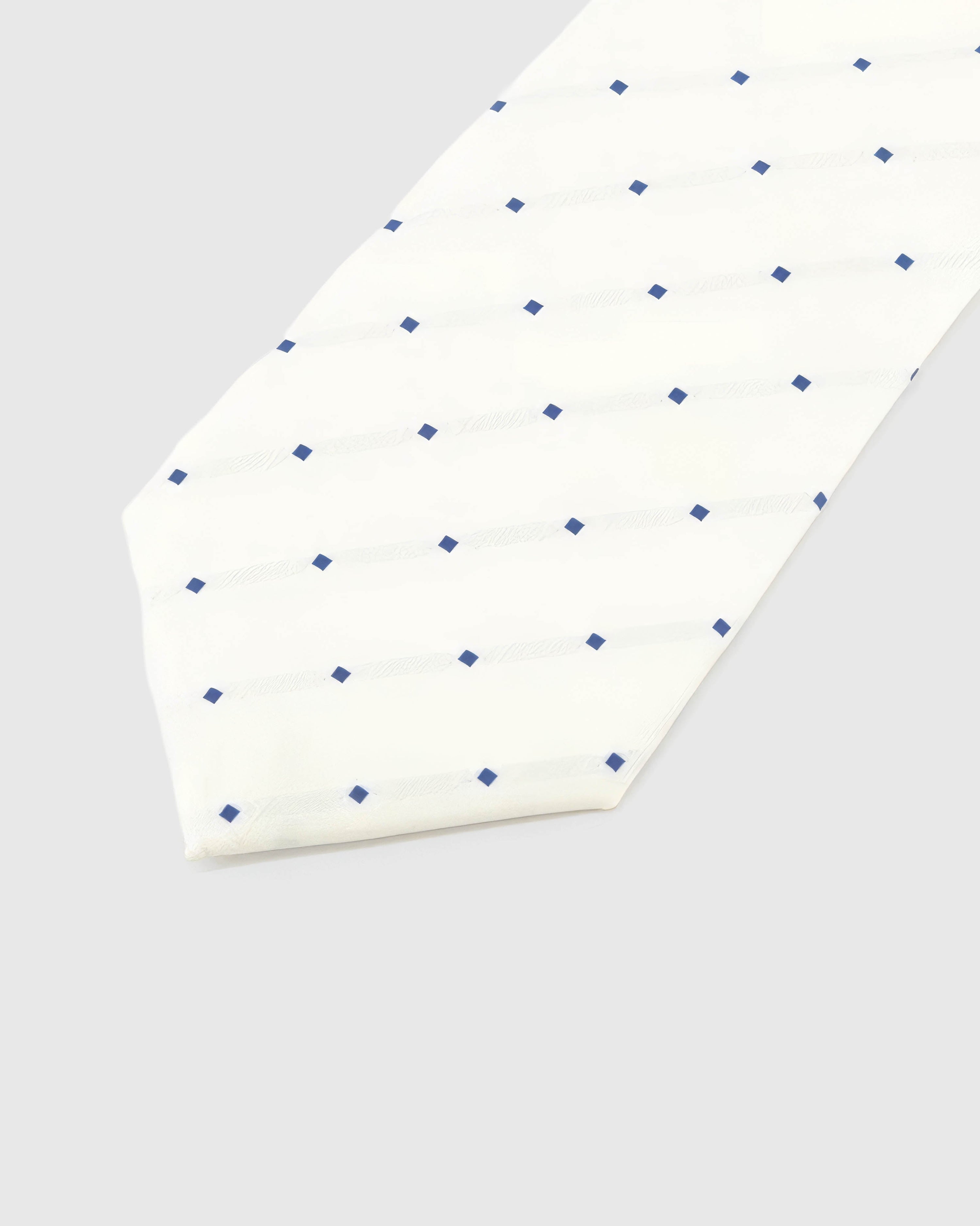 Ivory Navy Square Tie detail showing ivory ground with spaced navy squares and tonal lines and the tactile silk surface.
