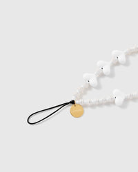 Close view of the glossy white hearts, ribbed disc beads, engraved gold-tone STICKYZOO disc and attachment loop.