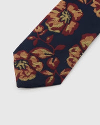 Navy Gilded Bloom Tie detail showing burgundy and gilded botanical blooms, raised thread and the tactile navy silk surface.