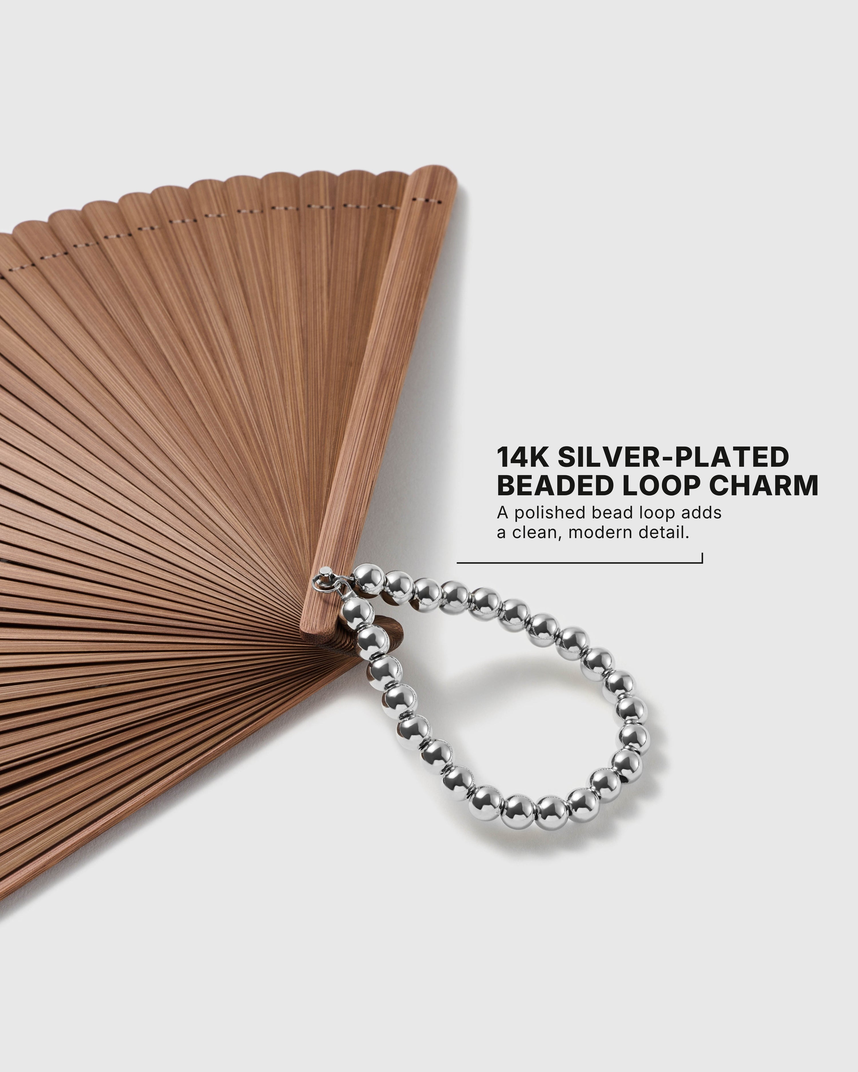 Close-up of 14K silver-plated beaded loop charm on the brown hand fan