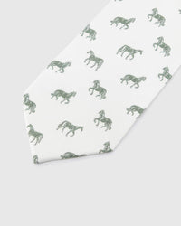 Ivory Equestrian Tie detail showing ivory ground with sage and forest horse silhouettes and the tactile silk surface.