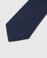 Midnight Micro-Square Tie detail showing midnight and indigo dense micro-square grid and the tactile silk surface.
