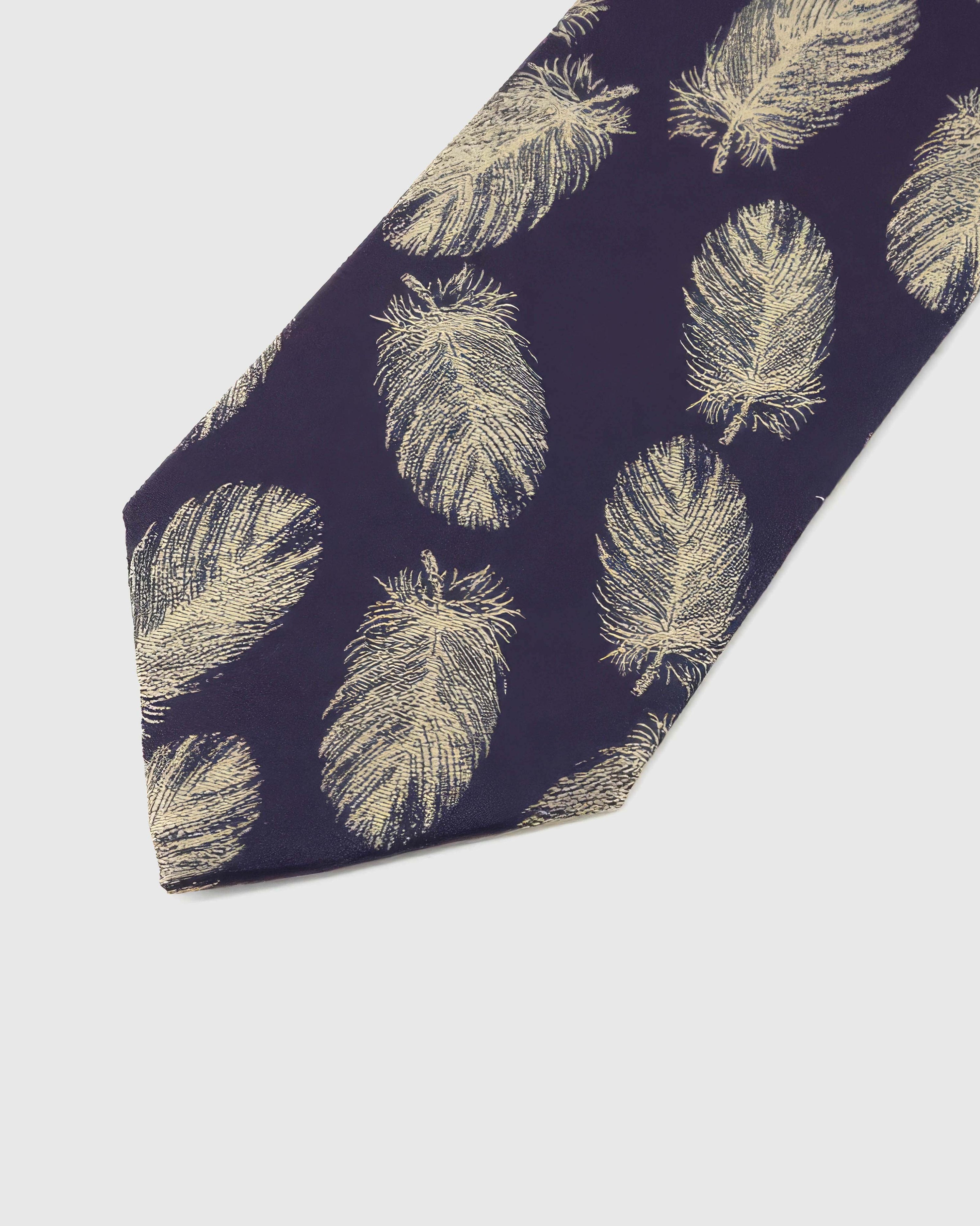 Aubergine Gilded Feather Tie detail showing pale-gold feather repeat, raised thread and the tactile aubergine silk surface.