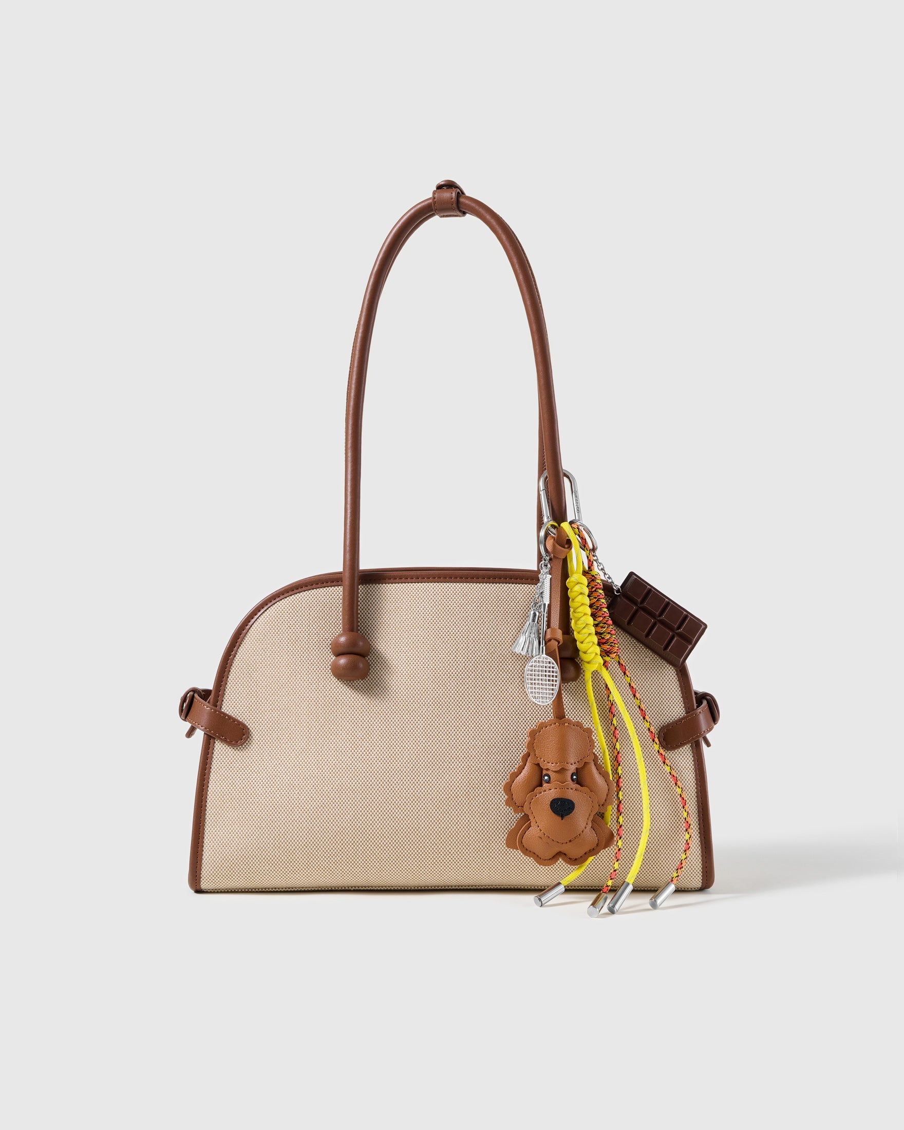 Poodle Chocolate Tennis Stack Charm attached to a structured handbag to show the complete design
