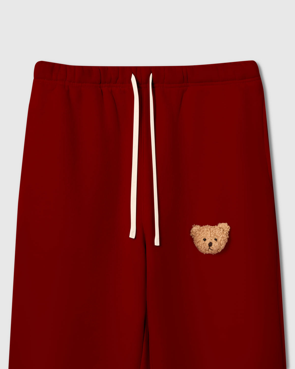 Close-up of plush teddy bear face on red cotton fleece showing sherpa texture and dimensional detail