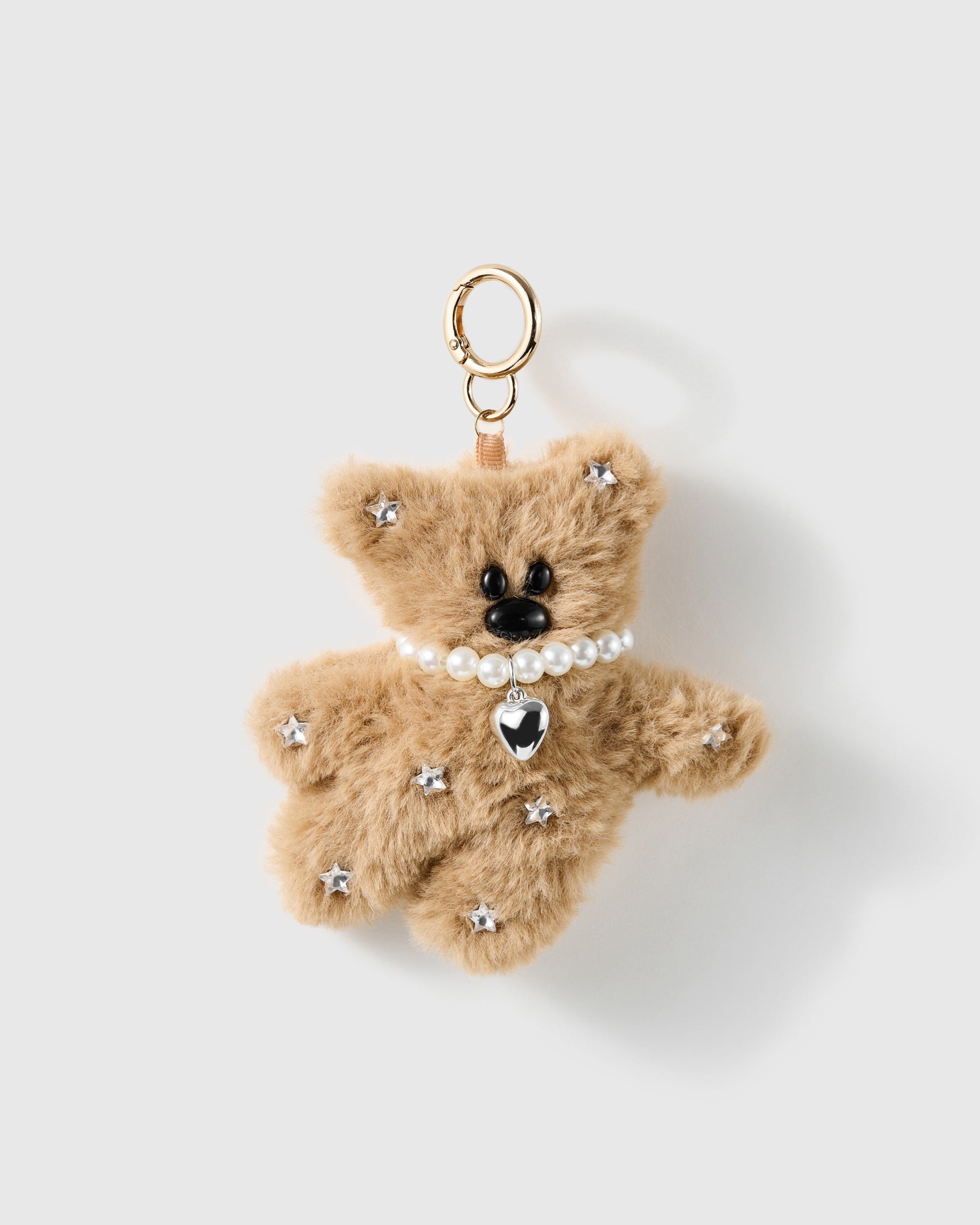 Stardust Pearl Teddy Charm, tan plush teddy with silver star accents, pearl-look necklace and heart pendant, on a light background