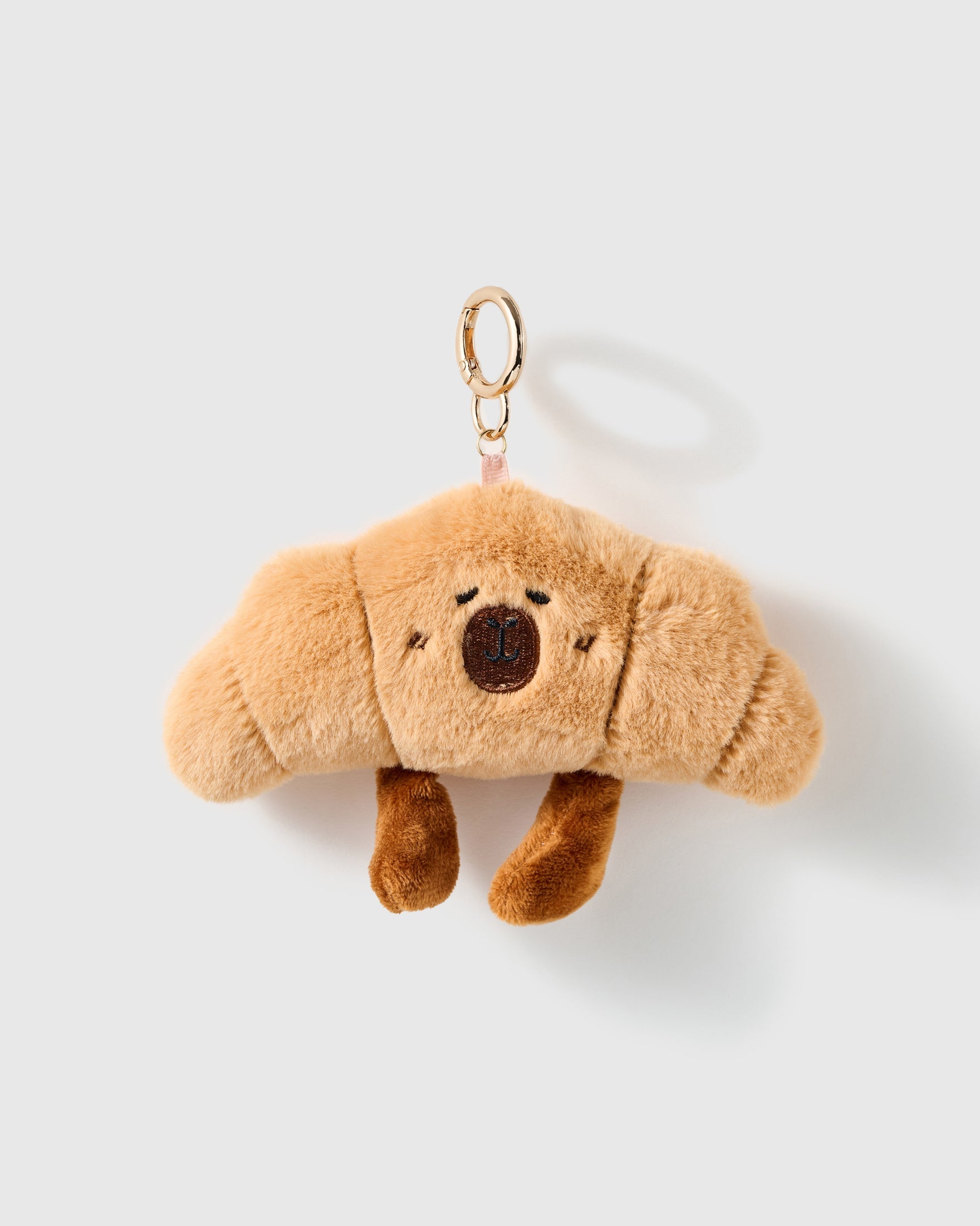 Snoozy Pup Charm, tan plush pup with closed embroidered eyes, floppy ears and dangling brown paws, on a light background