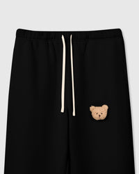 Close-up of plush teddy bear face on black cotton fleece showing dimensional sherpa texture