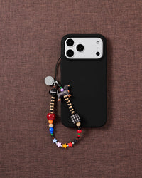 Dachshund Star beaded phone strap attached to a black phone case with the dog and multicolor stars visible.