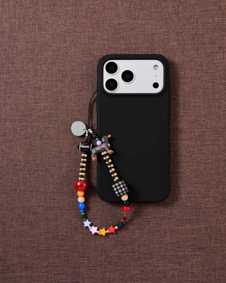 Dachshund Star beaded phone strap attached to a black phone case with the dog and multicolor stars visible.