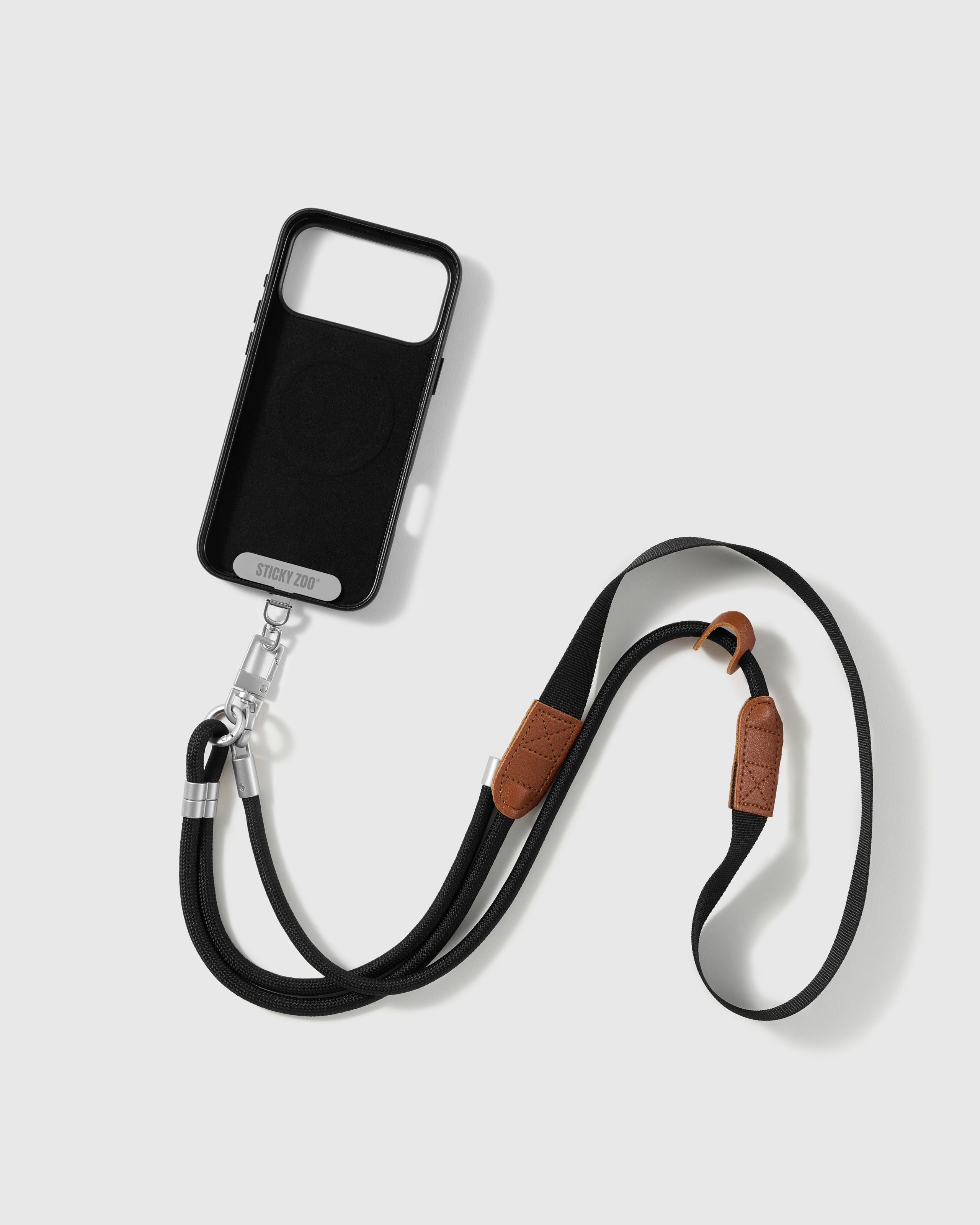STICKYZOO onyx cross-body phone strap attached to a black phone case using the included Phone Strap Card
