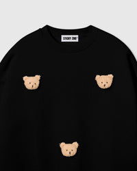 Detail of scattered bear face appliques on STICKYZOO black sweatshirt showing handmade craft