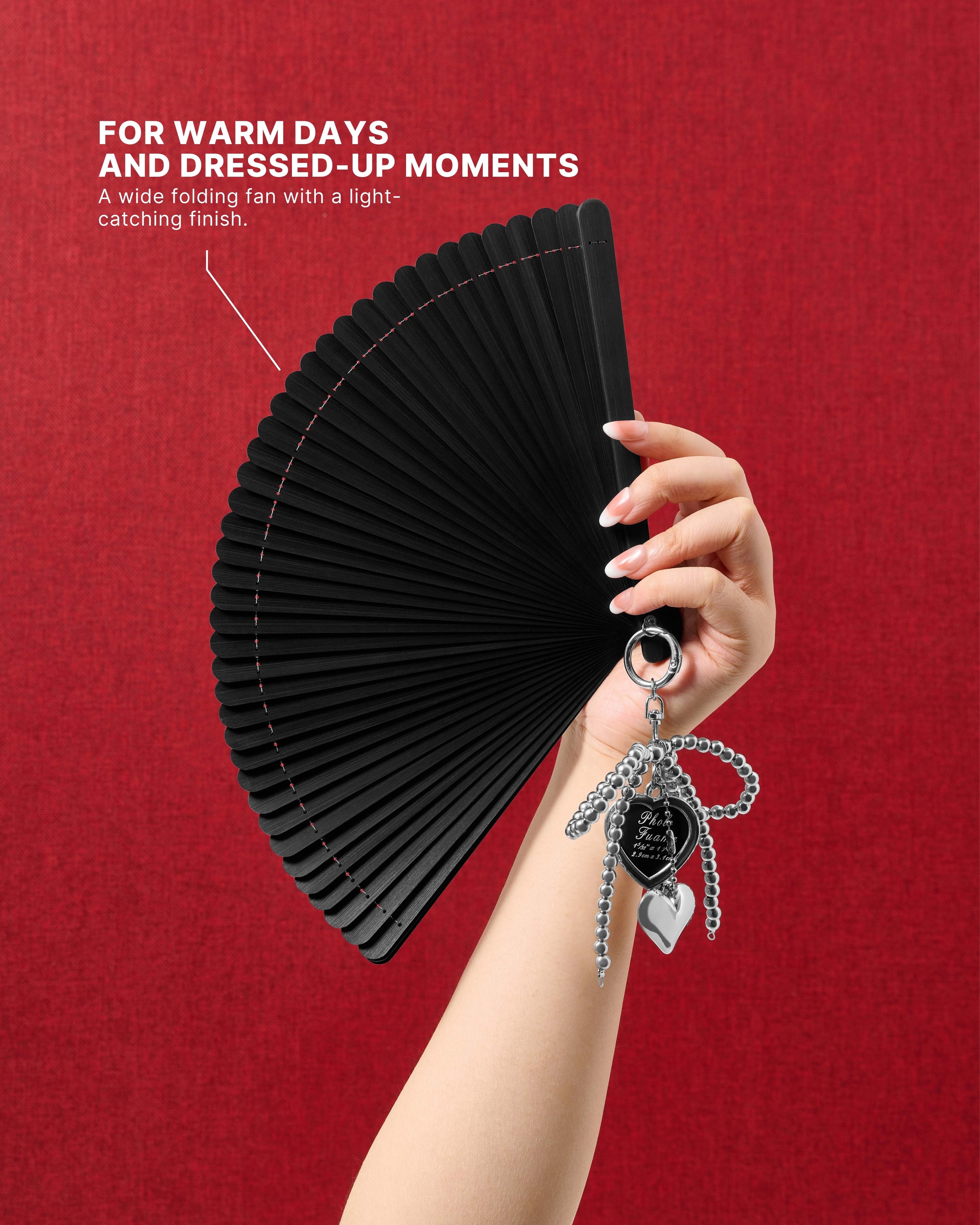 Onyx all-bamboo folding hand fan held against a red background