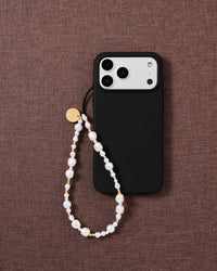Gilded Pearl beaded phone strap attached to a black phone case, showing the white faux-pearls and gold-tone bead pattern.