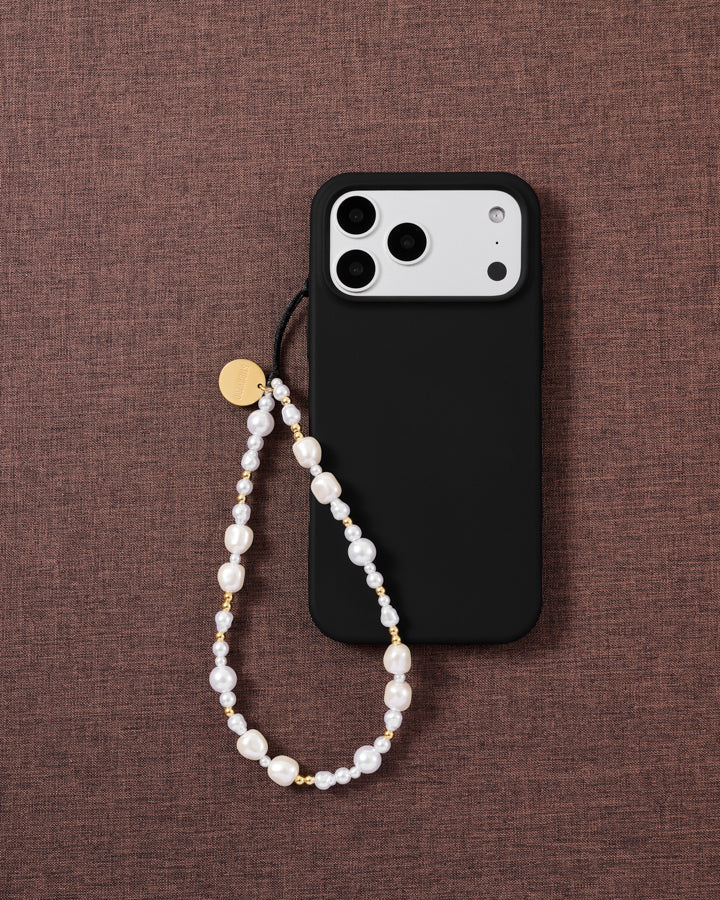 Gilded Pearl beaded phone strap attached to a black phone case, showing the white faux-pearls and gold-tone bead pattern.
