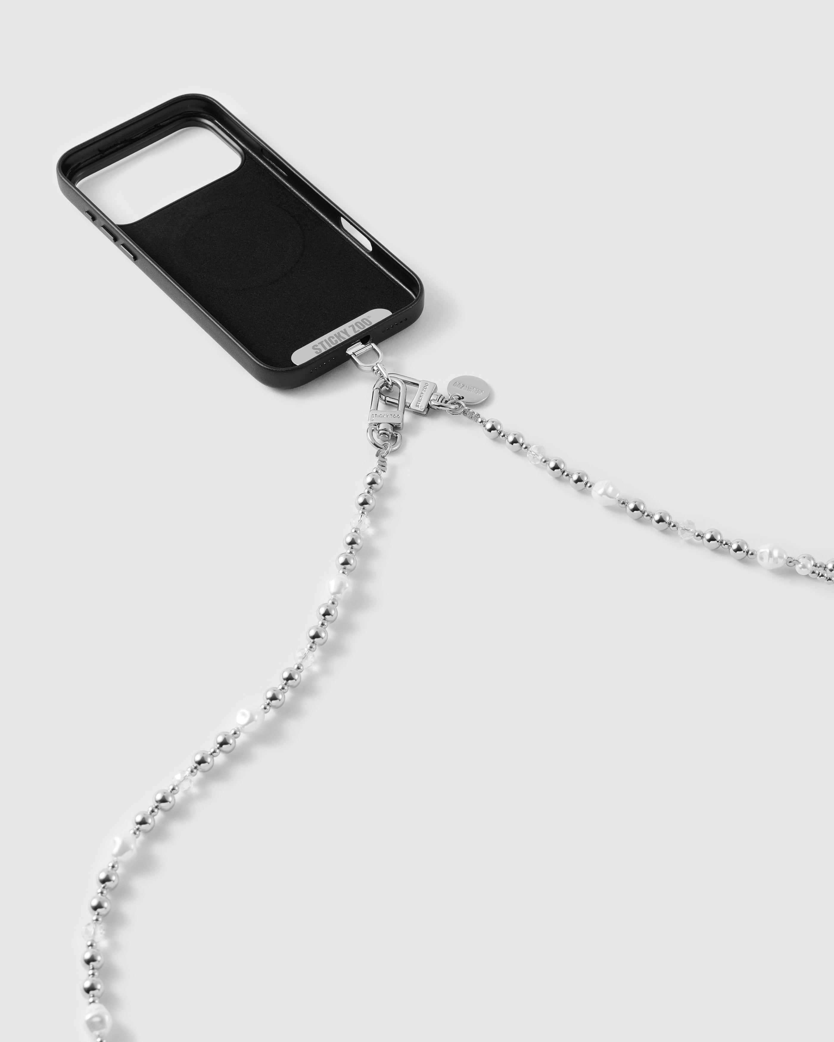 Dual silver-tone clasps and engraved disc connecting the beaded cross-body strap to a black phone case.
