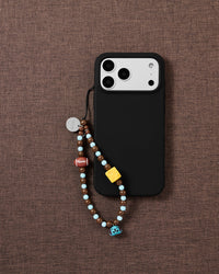 Game Day beaded phone strap attached to a black phone case with the football, cheese and blue puppy bell visible.