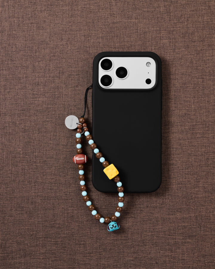 Game Day beaded phone strap attached to a black phone case with the football, cheese and blue puppy bell visible.