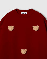 Detail view of scattered plush bear faces on STICKYZOO sweatshirt showing dimensional hand-stitched craft