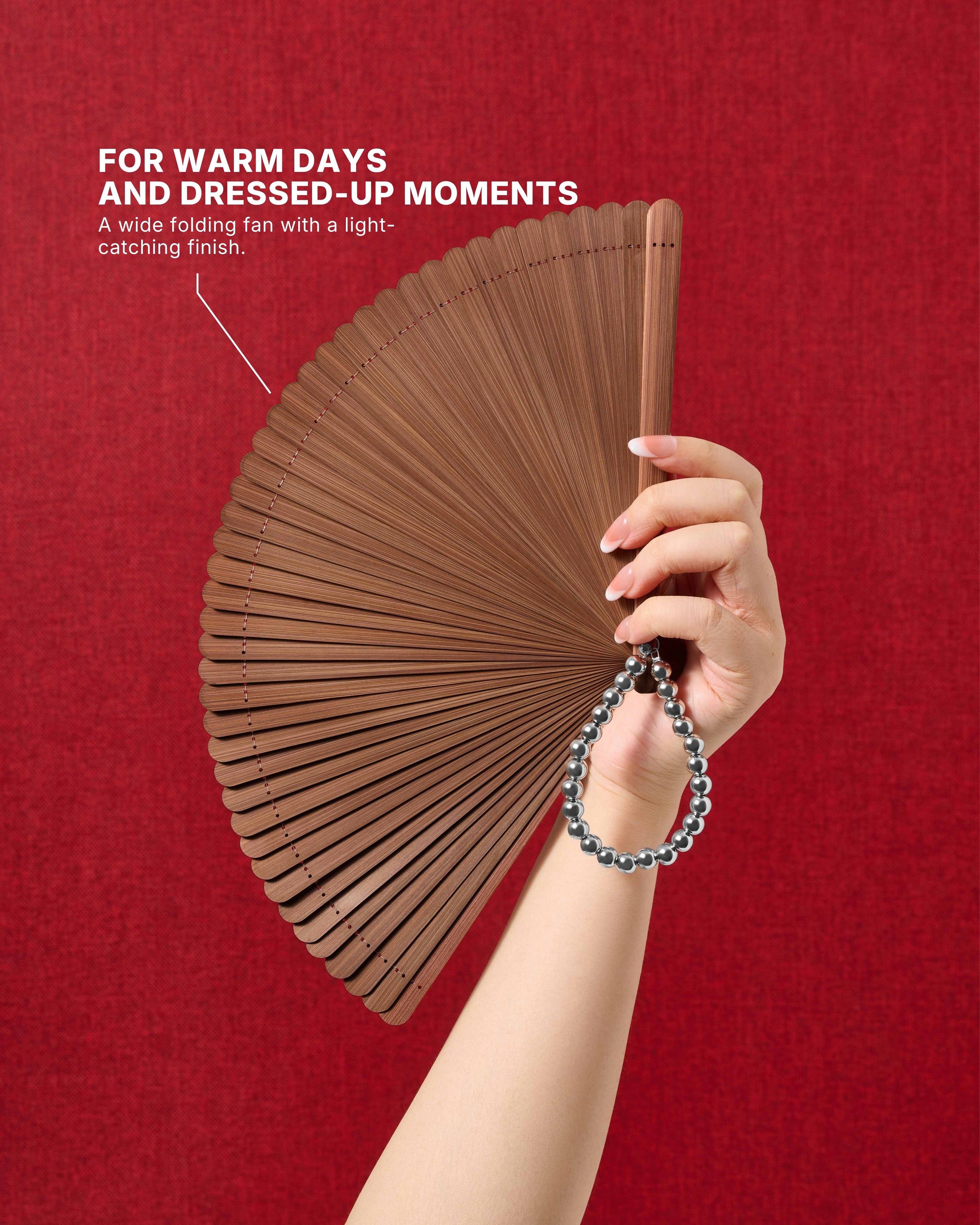 Espresso all-bamboo folding hand fan held against a warm background
