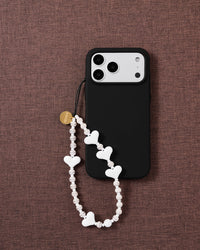 Snow Heart white beaded phone strap attached to a black phone case, showing the alternating heart and ribbed bead texture.