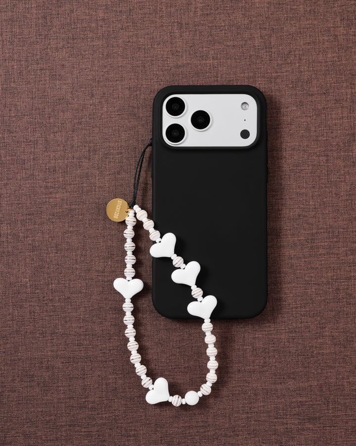Snow Heart white beaded phone strap attached to a black phone case, showing the alternating heart and ribbed bead texture.
