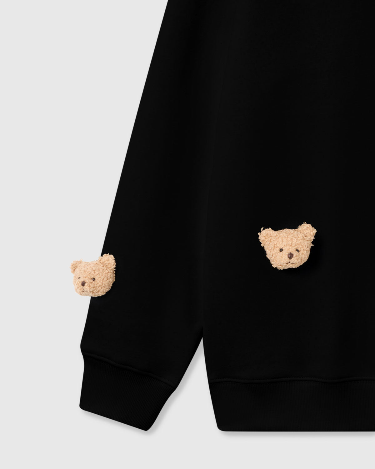 Close-up of plush teddy bear faces on black cotton showing dimensional 3D texture and embroidered details