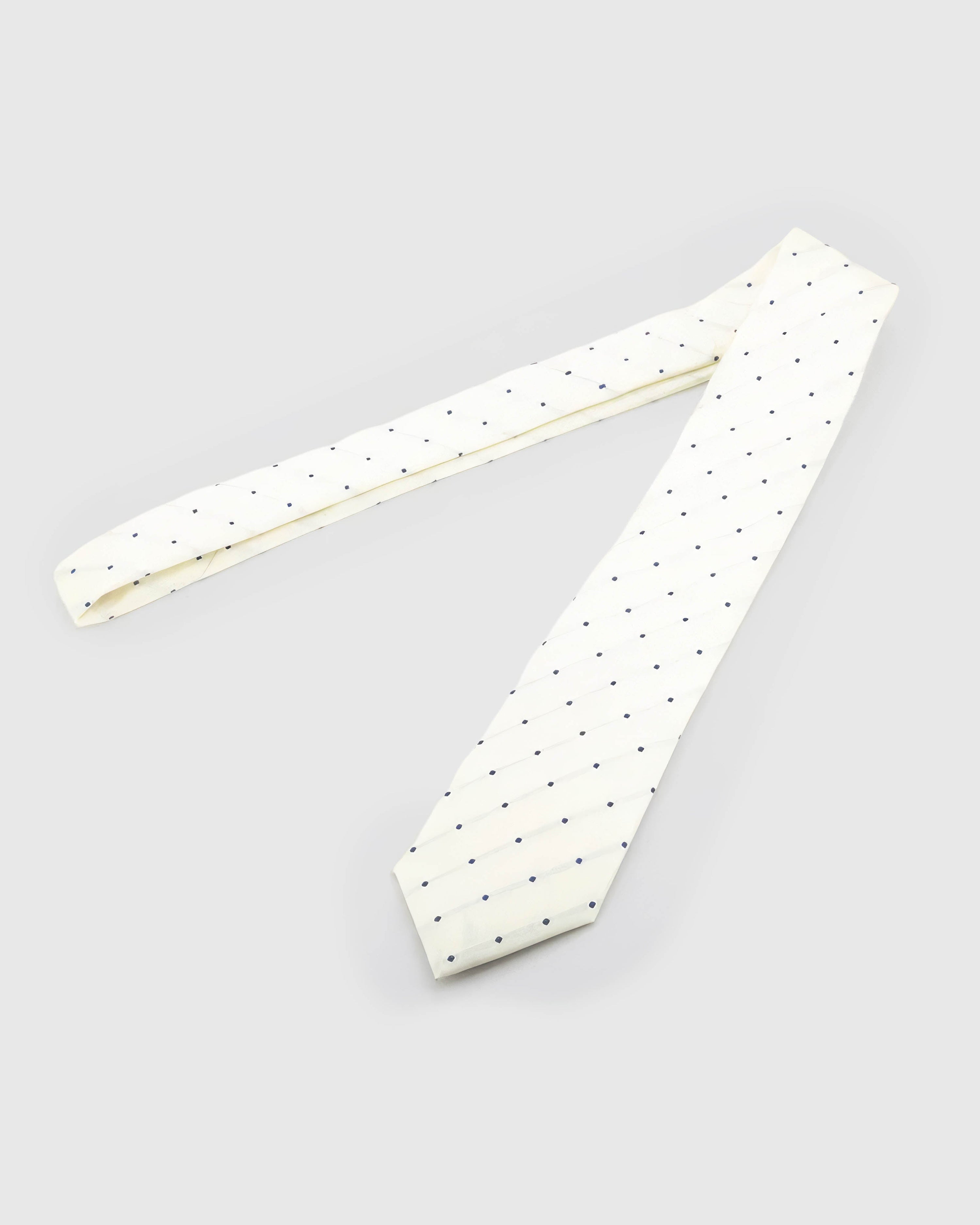 Ivory Navy Square Tie laid full length to show ivory ground with spaced navy squares and tonal lines from blade to tail.
