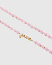 Macro close-up of the polished petal-pink resin beads and gold-plated clasp, each strap assembled by hand