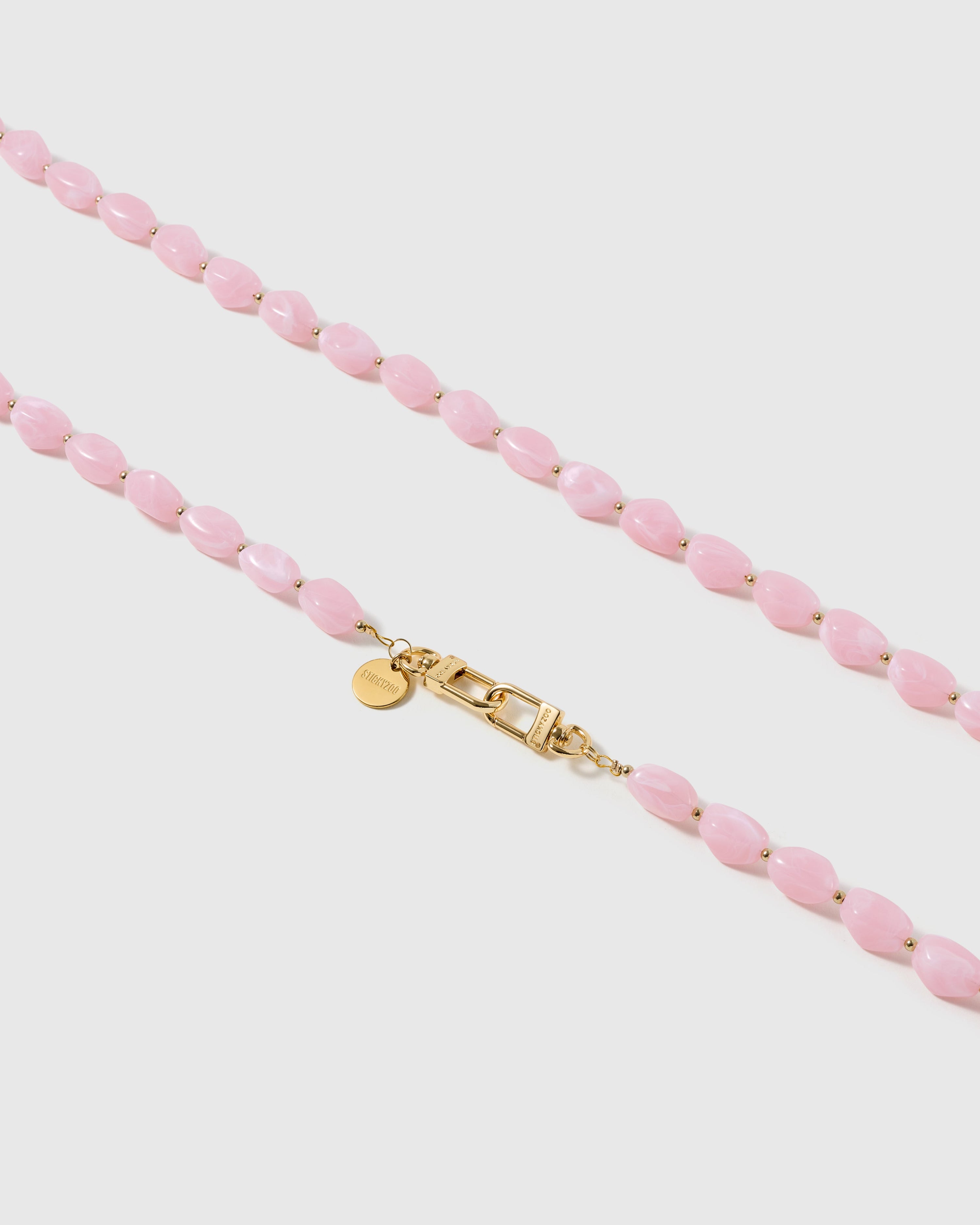 Macro close-up of the polished petal-pink resin beads and gold-plated clasp, each strap assembled by hand
