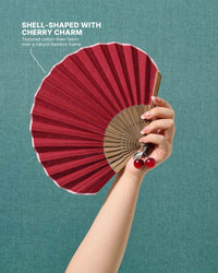 STICKYZOO cherry charm hand fan held open against a teal background