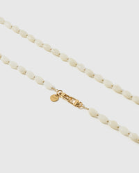 Macro close-up of the polished ivory resin beads and gold-plated clasp, each strap assembled by hand