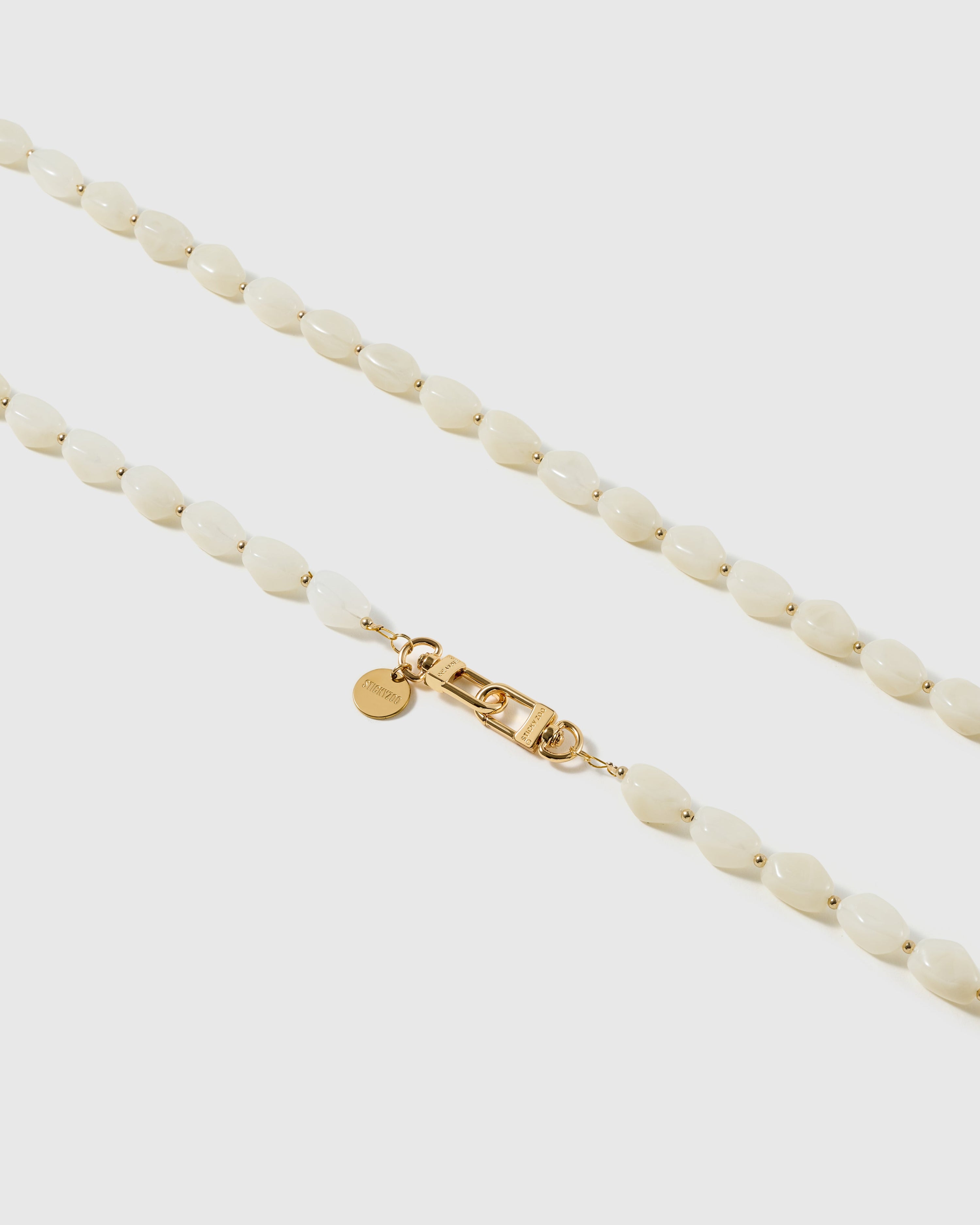 Macro close-up of the polished ivory resin beads and gold-plated clasp, each strap assembled by hand