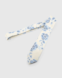 Ivory Porcelain Bloom Tie laid full length on white, showing an ivory ground with powder-blue and indigo blooms in a porcelain-inspired palette from blade to tail.