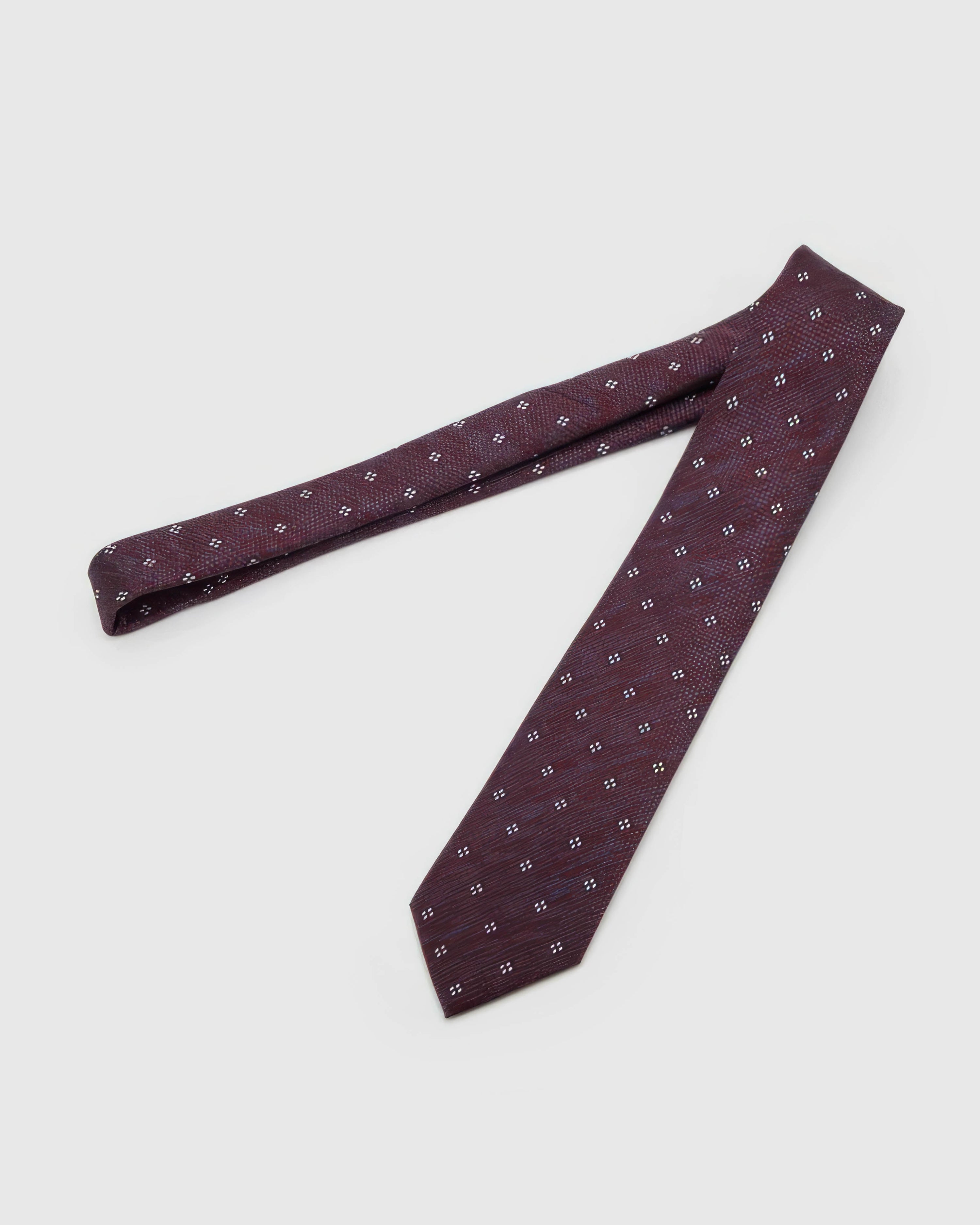 Claret Four-Dot Tie laid full length to show claret crosshatch with white four-dot clusters from blade to tail.