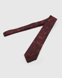 Garnet Shadow Bloom Tie laid full length to show garnet ground with tonal ember shadow blooms from blade to tail.