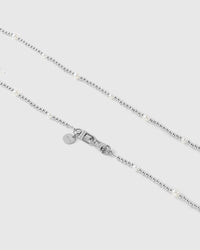 Close view of silver-tone ball beads, rounded faux-pearls, dual clasps and an engraved STICKYZOO disc.