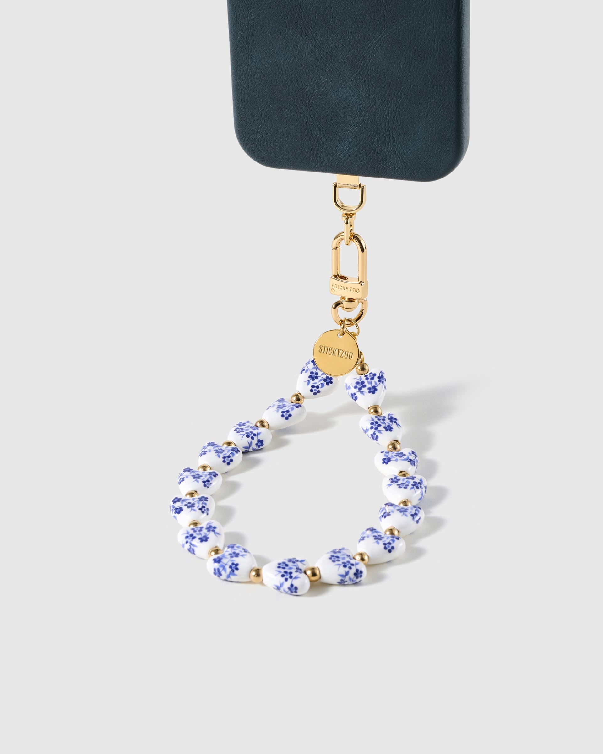 Porcelain heart wrist strap clipped to a black phone case for hands-free carry