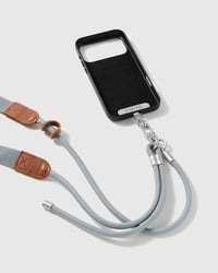 Mist-grey adjustable phone strap attached to a black phone case with sliding ring and stitched tan trim visible