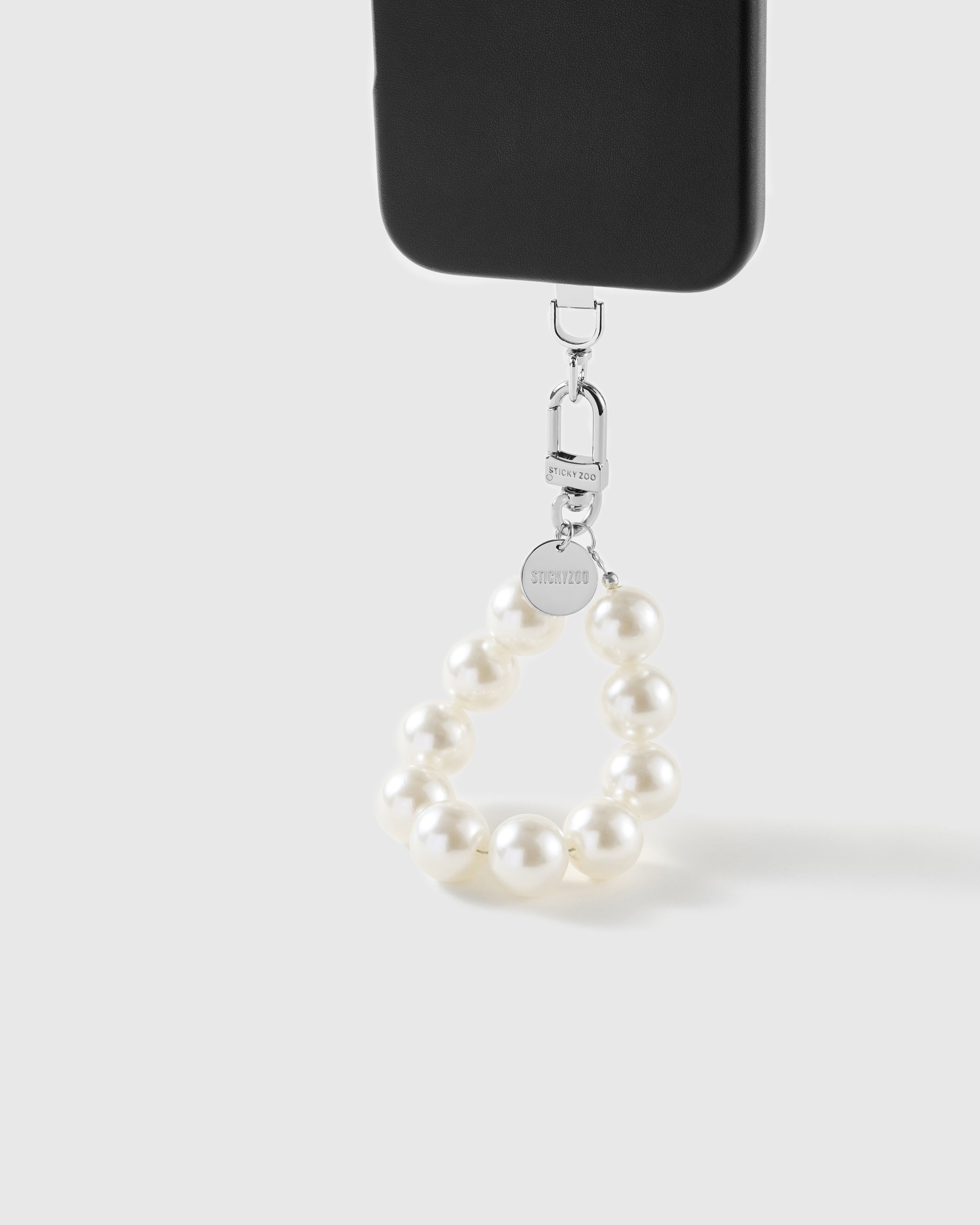 White pearl wrist strap clipped to a black phone case for hands-free carry
