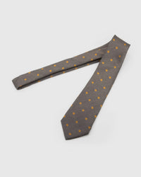 Pewter Herringbone Dot Tie laid full length on white, showing a pewter and charcoal herringbone field punctuated by small mustard-gold dots from blade to tail.