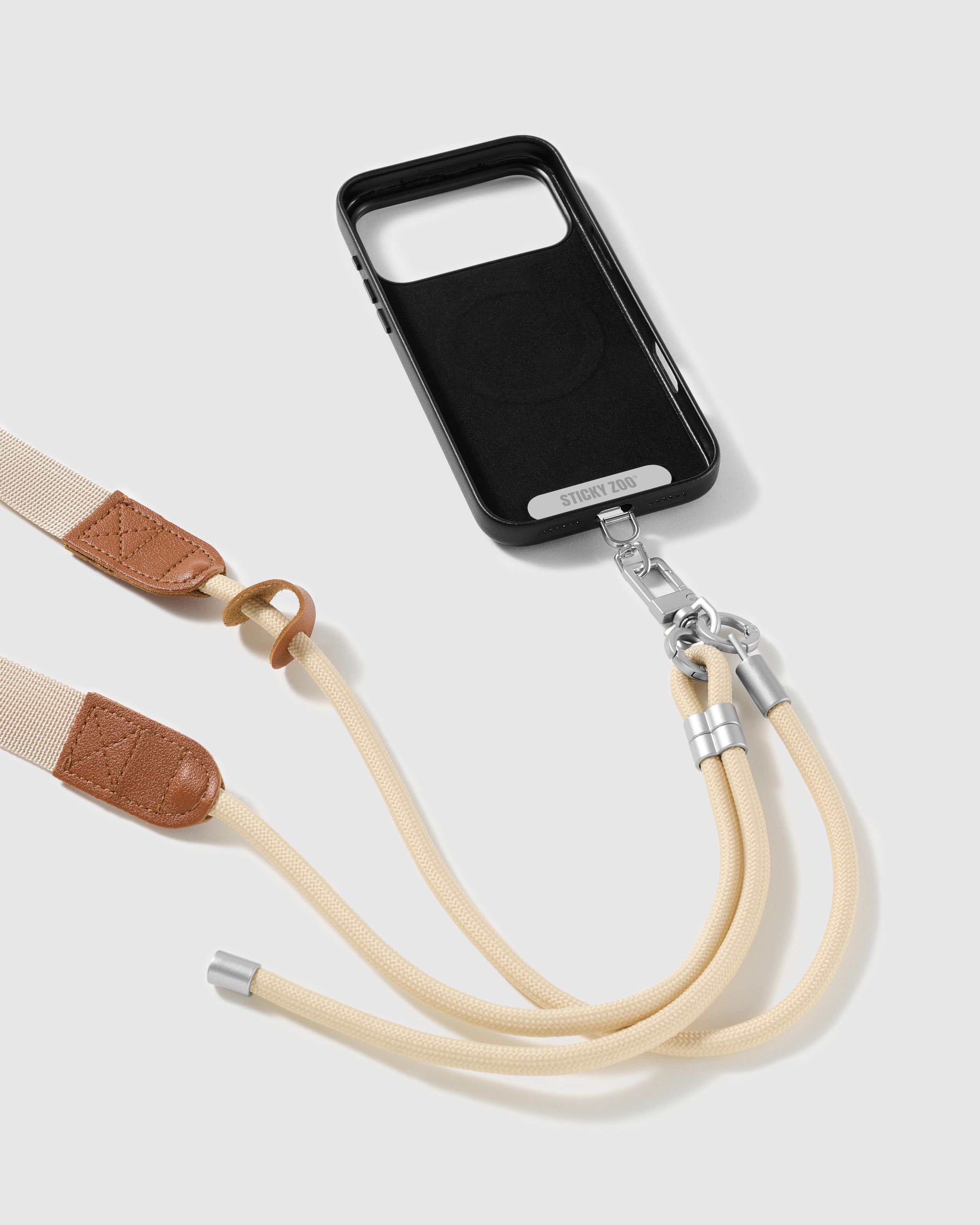 Ivory adjustable phone strap attached to a black phone case with the sliding ring and stitched tan trim visible