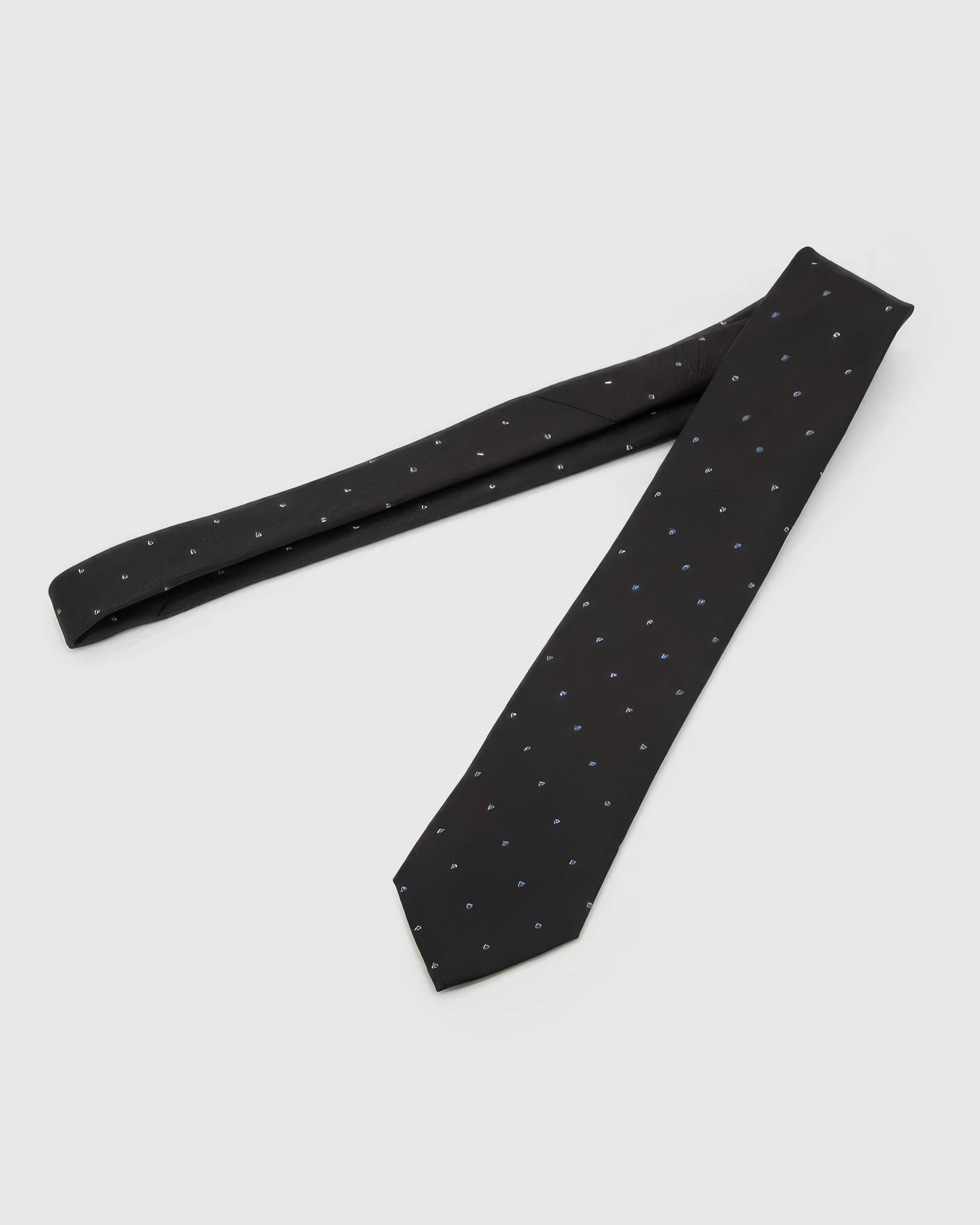 Noir Blue Icon Tie laid full length to show noir ground with small cobalt, azure and white abstract icons from blade to tail.