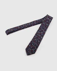 Midnight Crimson Meadow Tie laid full length on white, showing a midnight ground scattered with crimson micro-blooms and small cream leaves from blade to tail.