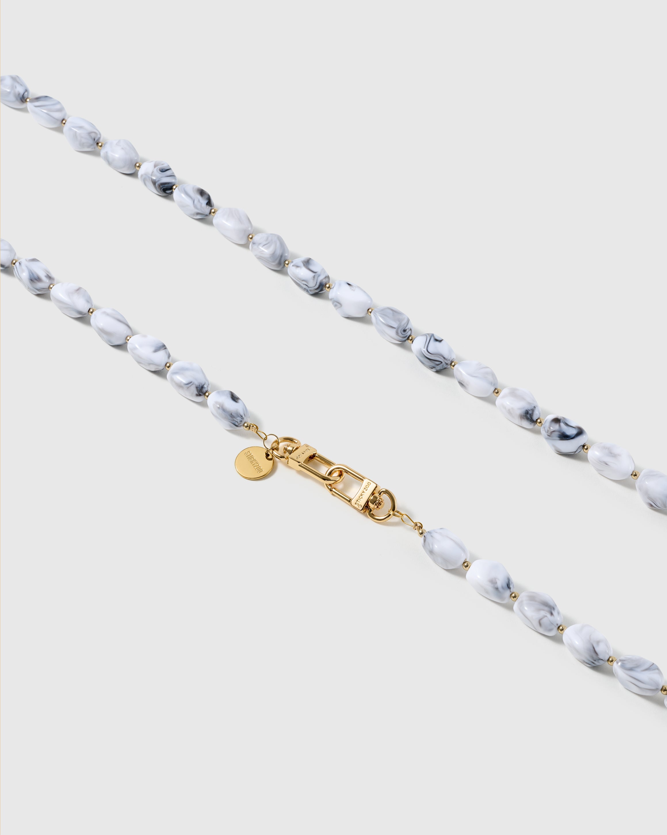 Macro close-up of the polished marble resin beads and gold-plated clasp, each strap assembled by hand