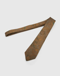 Umber Patina Tie laid full length to show umber and bronze patina with moss and amber forms from blade to tail.